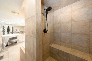 Full bathroom with a tile shower, vanity, and light tile patterned floors