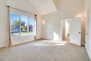 Unfurnished room with light colored carpet and high vaulted ceiling