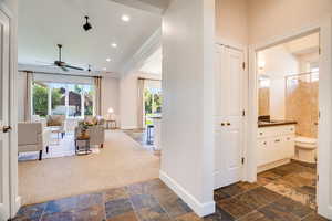 Hallway with dark colored carpet, healthy amount of natural light, stone tile flooring, recessed lighting, and crown molding
