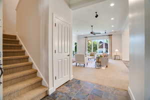 Carpeted living room featuring ornamental molding, stairway, stone tile floors, recessed lighting, and a ceiling fan