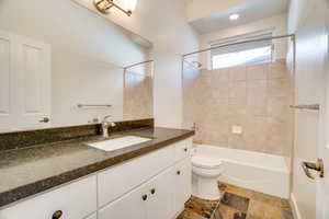Full bath with vanity, bathing tub / shower combination, and stone tile flooring