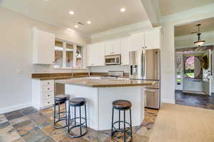 Kitchen featuring stainless steel appliances, a breakfast bar, stone tile flooring, ornamental molding, and dark stone counters