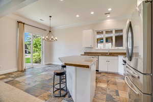 Kitchen featuring appliances with stainless steel finishes, white cabinetry, a kitchen bar, crown molding, and a kitchen island
