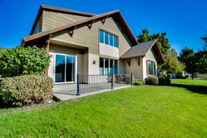 Rear view of property with a lawn and stucco siding