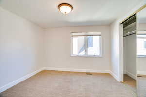 Unfurnished bedroom featuring a closet and light colored carpet