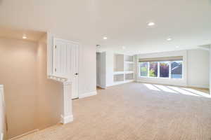 Basement featuring built in features, light colored carpet, and recessed lighting