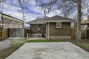 Rear view of property featuring brick siding, a patio, and a shingled roof
