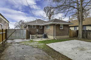 Rear view of house featuring a patio, brick siding, a shingled roof, and a gate