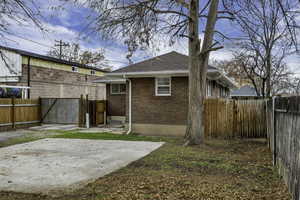 Back of property featuring a fenced backyard, brick siding, a patio, and roof with shingles
