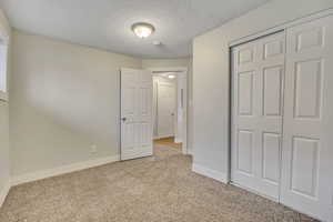 Unfurnished bedroom featuring carpet, a textured ceiling, and a closet