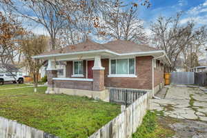 View of front facade with brick siding, a porch, roof with shingles, and driveway