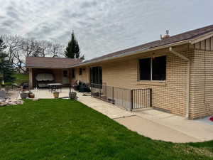 Rear view of house featuring a patio, brick siding, and a yard
