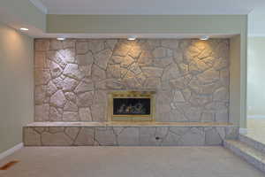 Detailed view of crown molding, carpet, and a fireplace