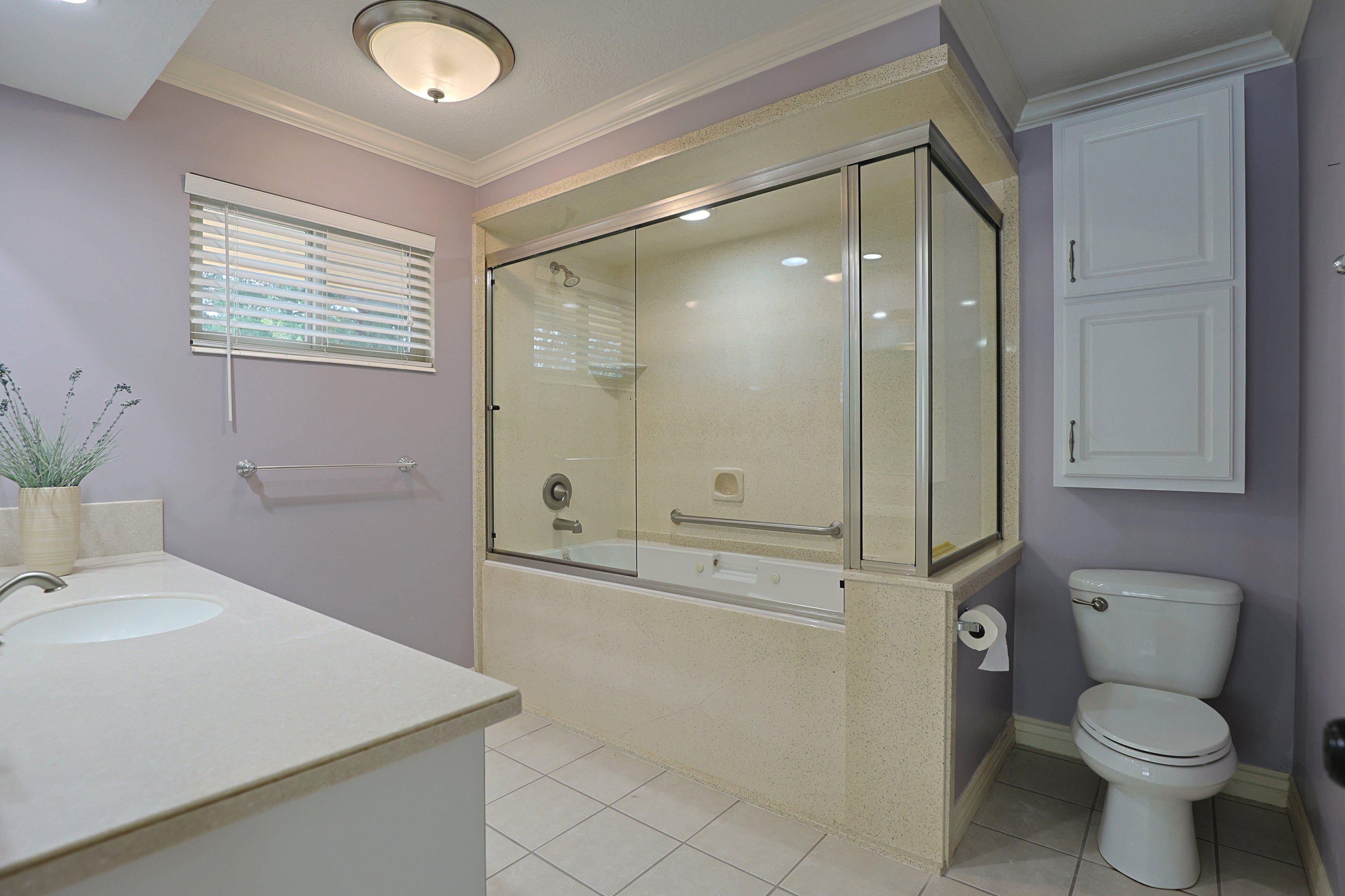 Full bath featuring vanity, light tile patterned floors, crown molding, and shower / bath combination with glass door