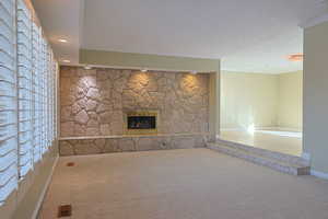 Unfurnished living room featuring a fireplace, carpet, crown molding, and recessed lighting