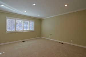 Carpeted empty room with a textured ceiling, recessed lighting, and ornamental molding