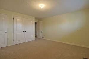 Unfurnished bedroom featuring a textured ceiling, carpet, and a closet