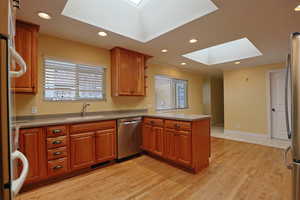 Kitchen featuring a skylight, recessed lighting, a peninsula, stainless steel appliances, and plenty of natural light