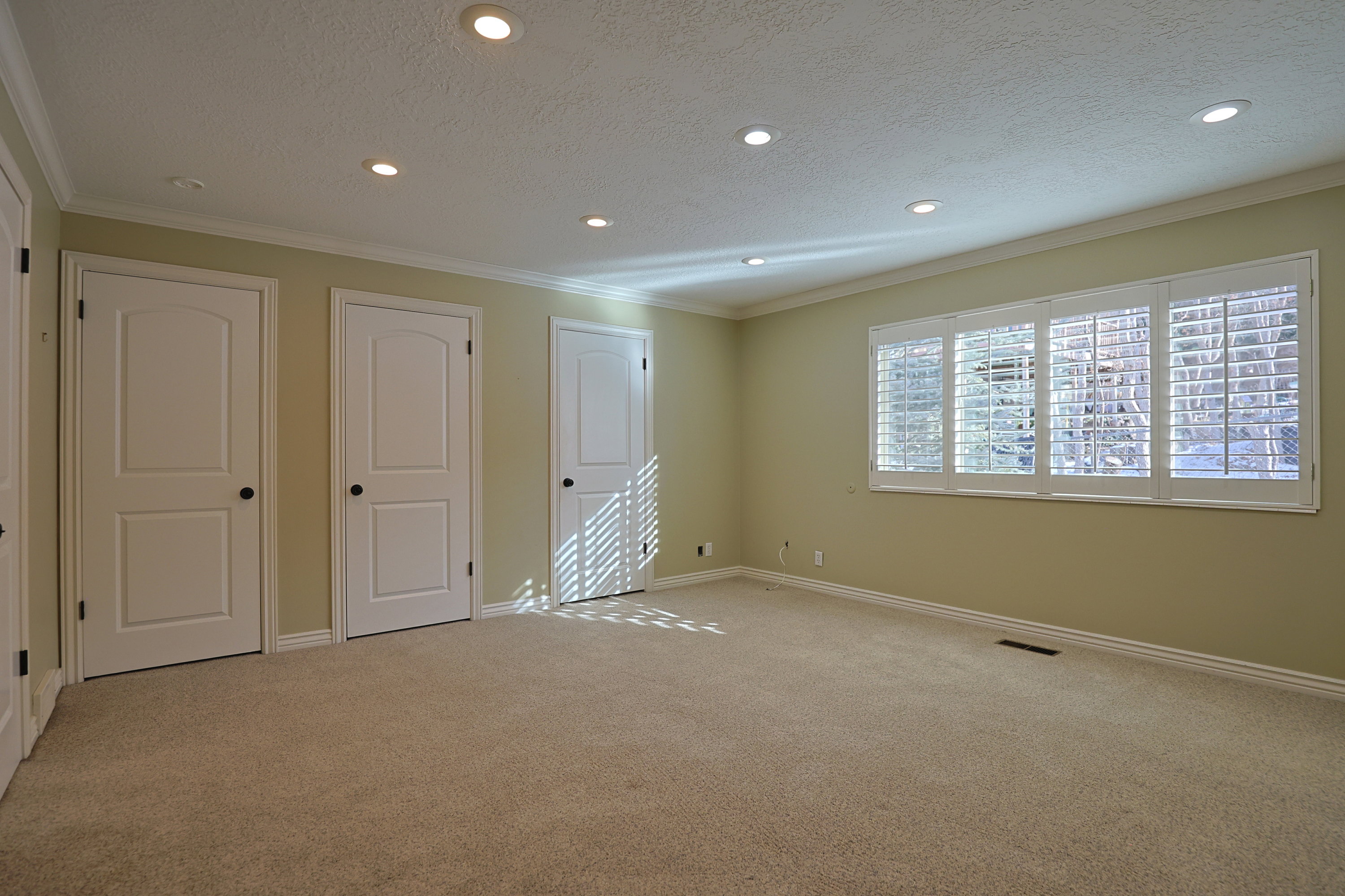 Unfurnished bedroom featuring a textured ceiling, ornamental molding, carpet flooring, recessed lighting, and multiple closets