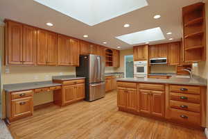 Kitchen featuring open shelves, a peninsula, recessed lighting, a skylight, and appliances with stainless steel finishes