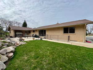 Back of property with a patio, brick siding, and a lawn