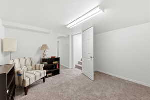 Living area featuring light colored carpet, a textured ceiling, and stairway