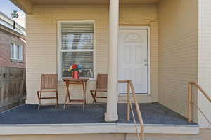 Doorway to property featuring brick siding and covered porch