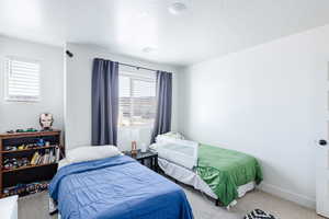 Carpeted bedroom featuring a textured ceiling and baseboards