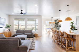 Living room featuring light wood-style flooring, a textured ceiling, a ceiling fan, and recessed lighting