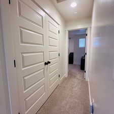 Corridor with light colored carpet and baseboards