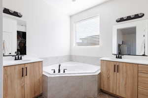 Full bath featuring two vanities, a garden tub, and dark tile patterned floors