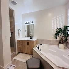 Bathroom featuring a bath, vanity, light tile patterned floors, a walk in shower, and a textured ceiling