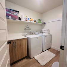 Washroom with light wood-type flooring and washer and dryer