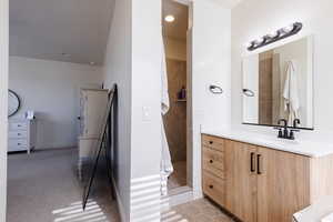 Full bath featuring vanity, a walk in shower, light tile patterned floors, and light carpet
