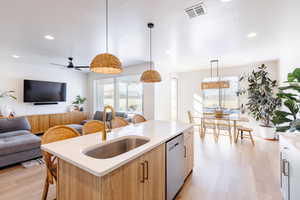 Kitchen with open floor plan, a breakfast bar area, light wood-style floors, light stone countertops, and a textured ceiling