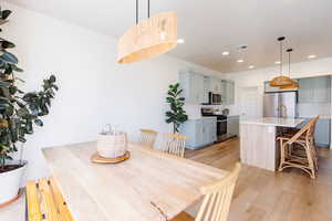 Dining room with light wood finished floors and recessed lighting