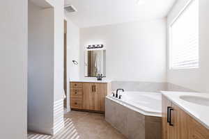 Bathroom with vanity, light tile patterned floors, and a garden tub