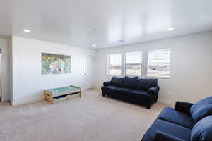 Living room featuring a textured ceiling, light colored carpet, and recessed lighting
