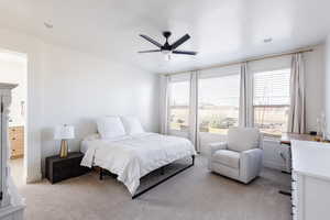 Bedroom with light carpet, a ceiling fan, a textured ceiling, and ensuite bathroom