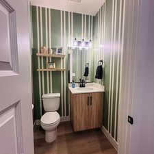 Bathroom with vanity, dark wood-style floors, and wallpapered walls