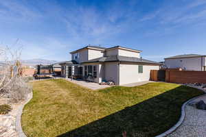 Back of house with stucco siding, a fenced backyard, a trampoline, a patio area, and a mountain view