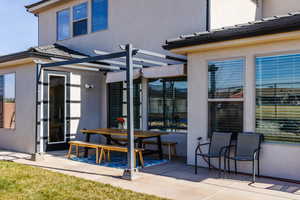Rear view of property featuring outdoor dining area, a patio area, stucco siding, a tile roof, and a pergola