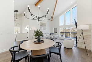 Dining room with a chandelier, high vaulted ceiling, light wood-style flooring, and beamed ceiling