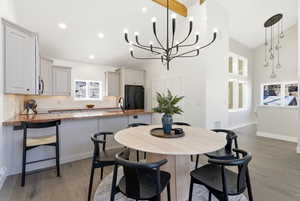 Dining space with high vaulted ceiling, light wood-style flooring, and a chandelier