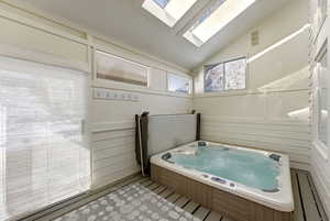 Full bathroom featuring a skylight, a bath, and lofted ceiling