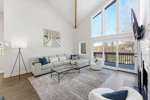 Living area featuring a brick fireplace, high vaulted ceiling, and wood finished floors