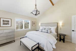 Carpeted bedroom with high vaulted ceiling and beam ceiling