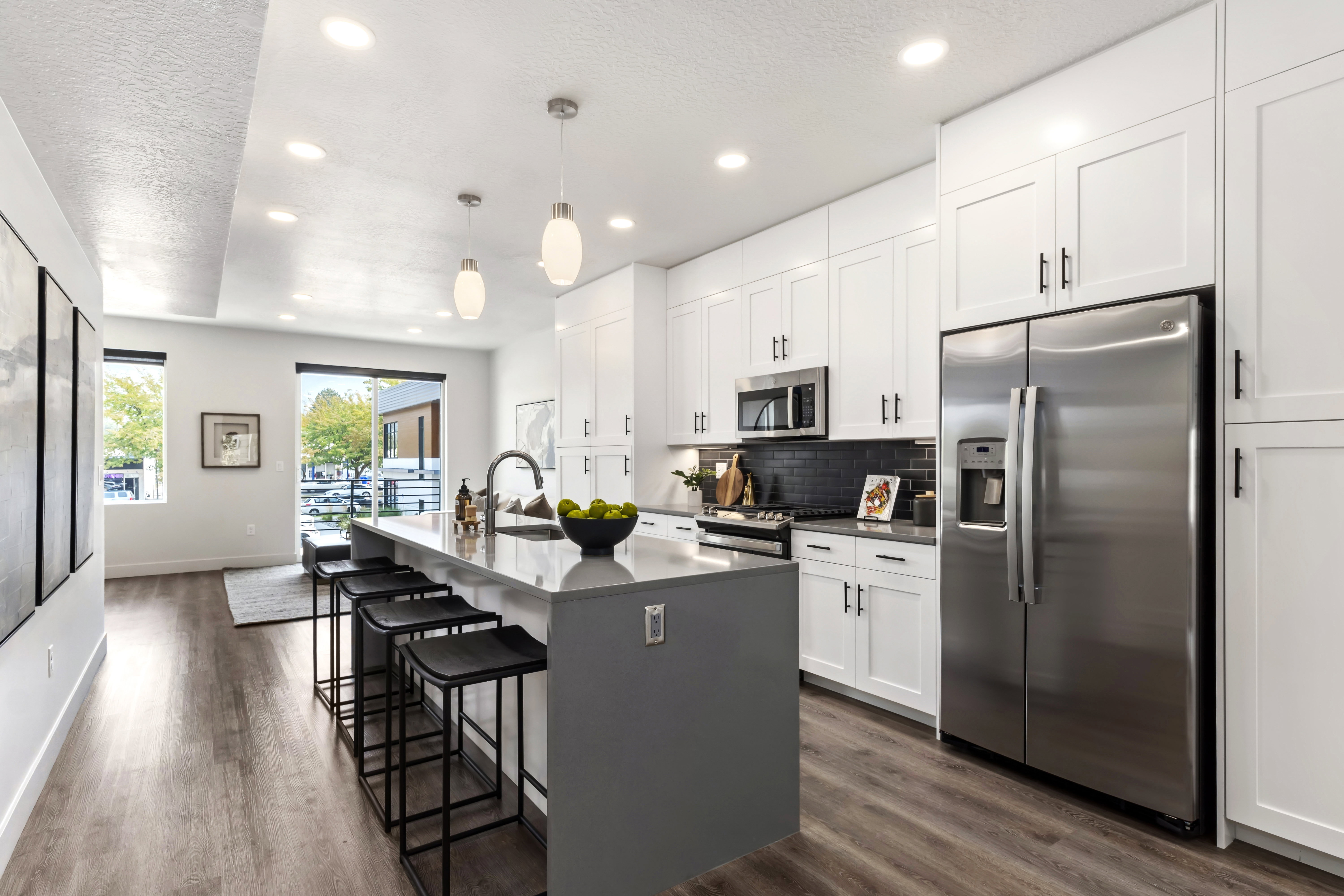 Kitchen featuring stainless steel appliances, white cabinetry, recessed lighting, a kitchen bar, and an island with sink. Model Home