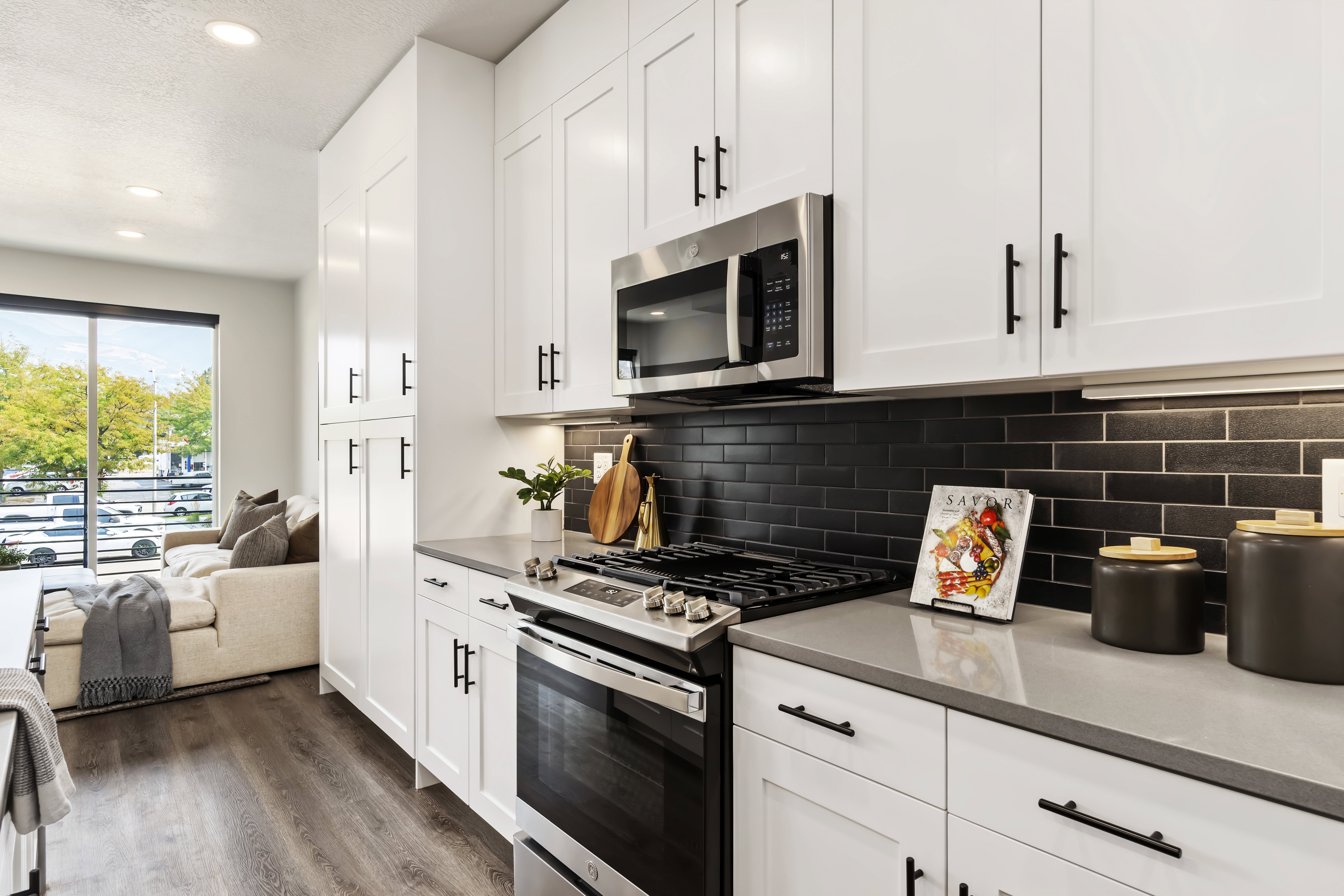 Kitchen featuring stainless steel appliances, white cabinetry, dark wood-style floors, recessed lighting, and light stone counters. Model Home