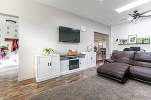 Living room featuring ceiling fan, dark wood-style flooring, and a textured ceiling